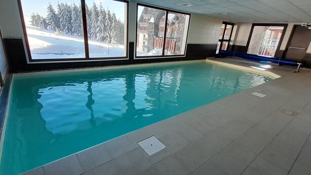Una piscina interior amb vistes clares a un paisatge nevàs a través de grans finestres.