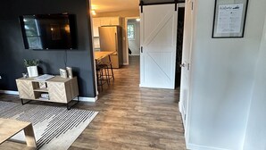 Ein modernes Interieur mit Holzboden, einem an der Wand montierten Fernseher, einer Schiebetür und einem gerahmten Willkommensschild.