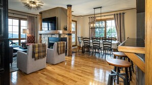 Un salón espacioso con chimenea, asientos cómodos y un comedor con mesas y sillas de madera.