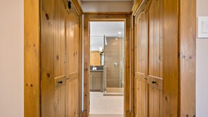 Un pasillo de madera que conduce a un baño con ducha y lavamanos.