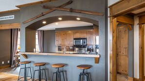 Una cocina moderna con armarios de madera, un microondas integrado y una zona de bar con taburetes.