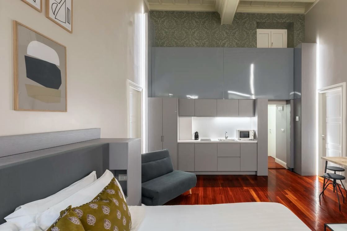 Un espacio habitable compacto con cama, sofá, kitchenette y comedor.