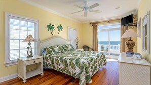 A bedroom with a bed, two nightstands, a ceiling fan, a TV, and a view of the ocean. - 7-Bedroom Home w/ Private Pool & Ocean Views (Surfside Beach)