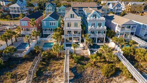 A coastal residential area with multiple two-story houses featuring balconies, a swimming pool, and a wooden boardwalk. - 7-Bedroom Home w/ Private Pool & Ocean Views (Surfside Beach)