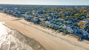 An aerial view of a coastal residential area with beachfront properties, a sandy beach, and a dense tree line in the background. - 7-Bedroom Home w/ Private Pool & Ocean Views (Surfside Beach)