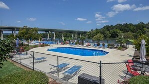 A swimming pool with lounge chairs and a fenced area. - The Container Home at River Rocks Landing (Gadsden)