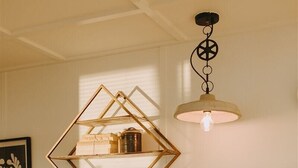 A kitchen with a sink, a wooden table, a pendant light, and a geometric shelf. - The Container Home at River Rocks Landing (Gadsden)