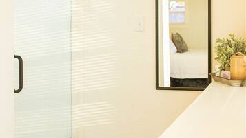 A room with a sliding glass door, a mirror on the wall, a white countertop, and a wooden floor.