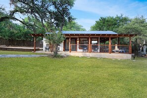 Une structure en bois dotée d’un patio couvert, de grandes fenêtres et d’un espace clos.