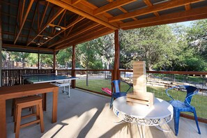 Une terrasse extérieure avec une table de ping-pong, une table en bois et des chaises.