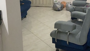 Ein Zimmer mit einer weißen Tür, einem blauen Sofa und einem grauen Sofa. Auf dem Boden in der Nähe der Tür liegen Taschen.