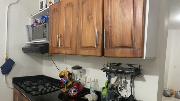 Eine Küche mit Holzausstattung, einem Gasherd, einem Mixer und verschiedenen Küchenutensilien.