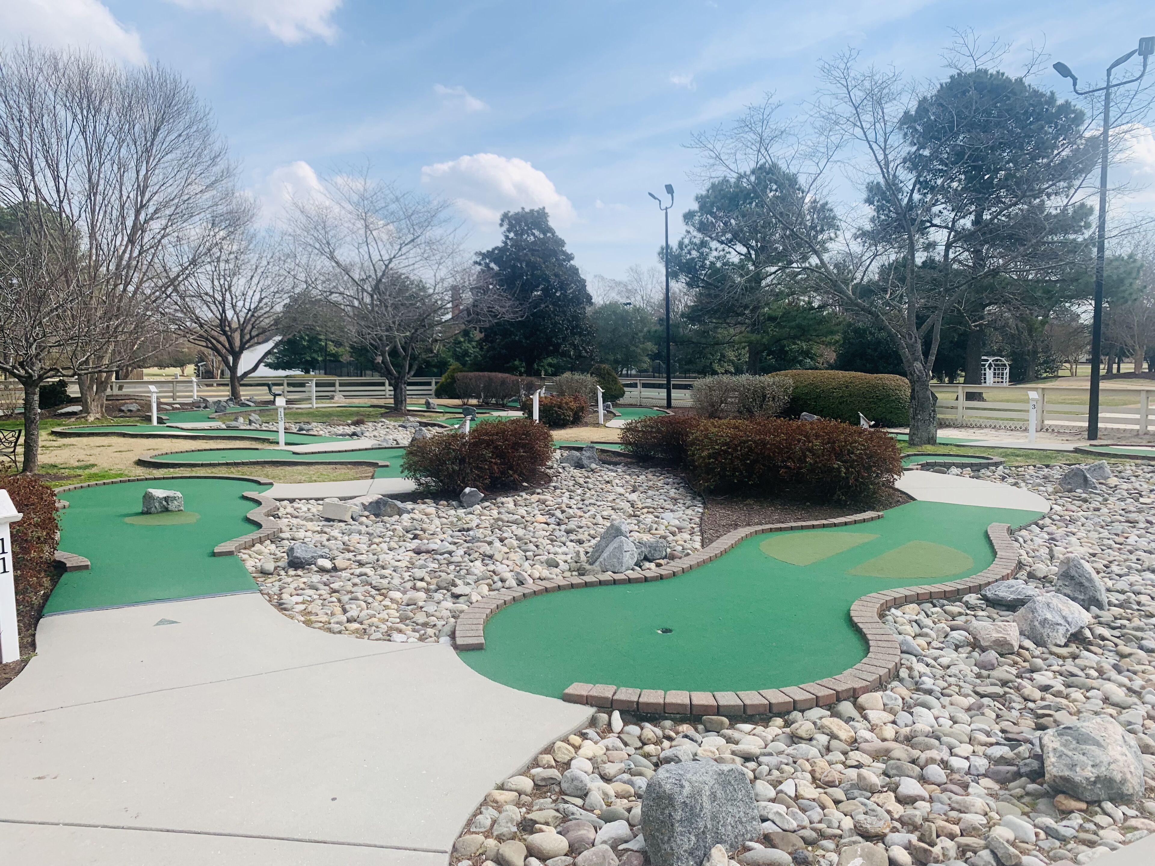 Un parcours de mini-golf avec des verts impeccables, un chemin sinueux et des aménagements paysagers environnants.