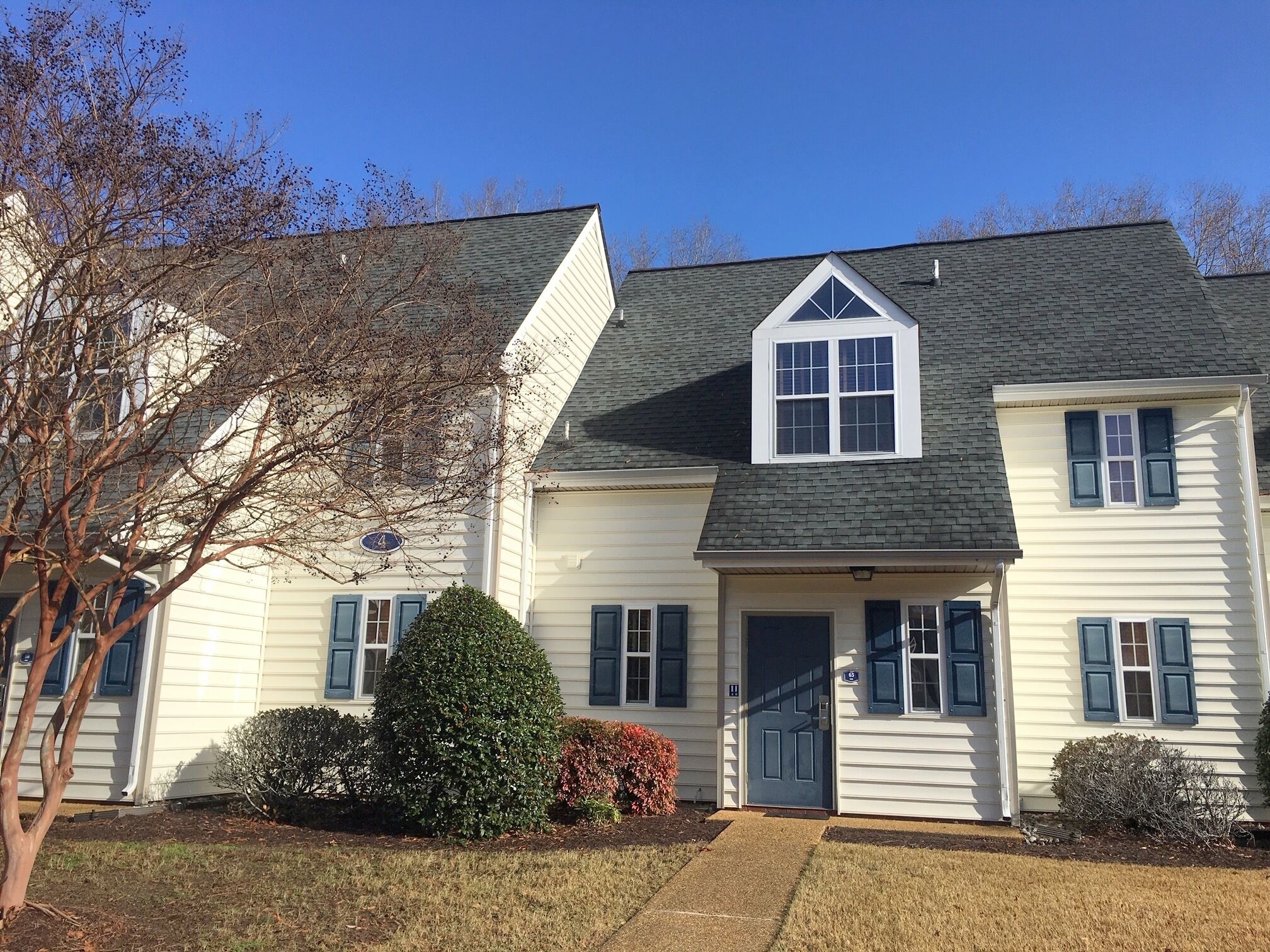 A two-story house with a gabled roof, a front door, and a small triangular window above the door.