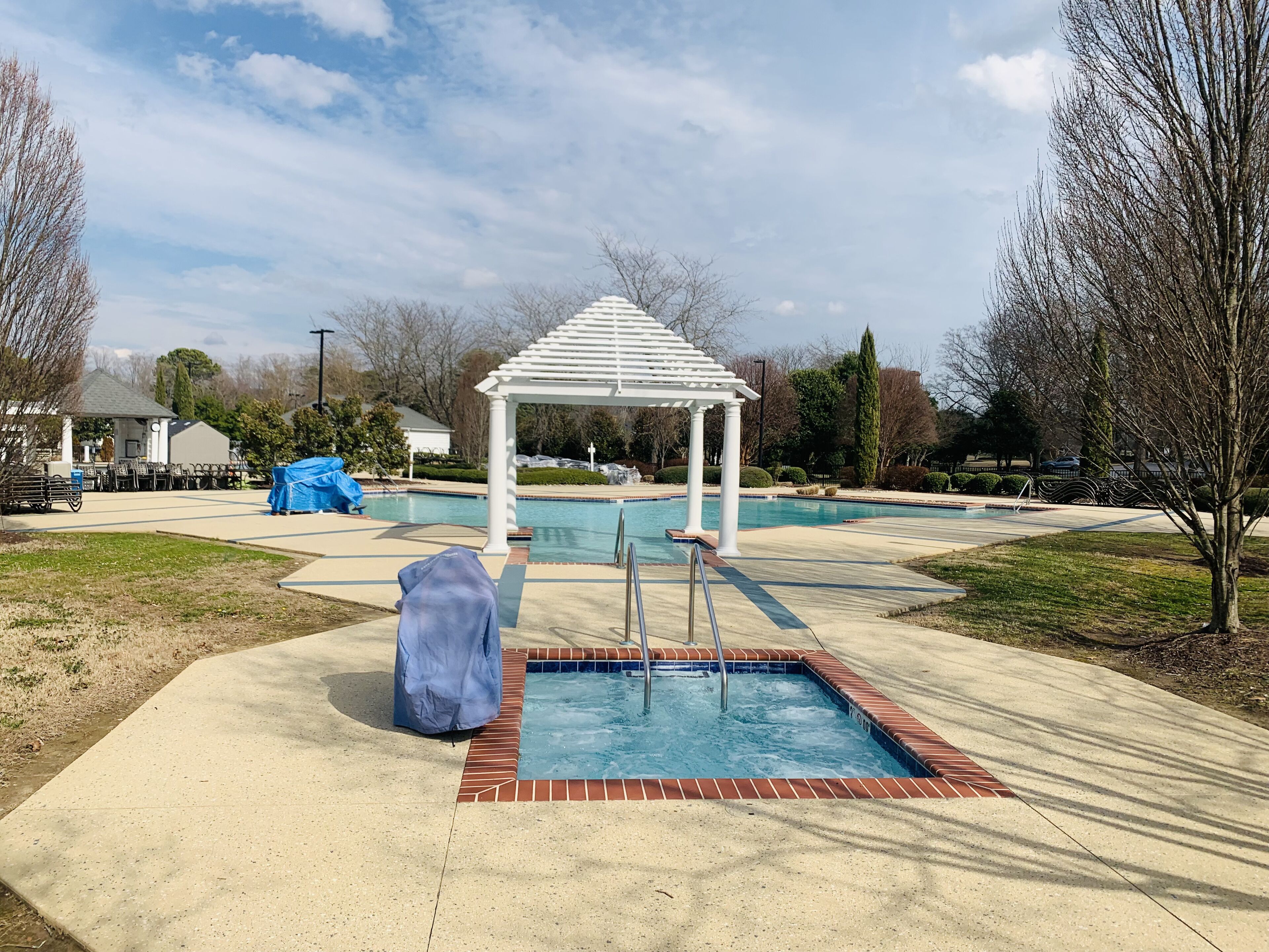 A pool area with a white gazebo, a small pool, and a covered seating area.