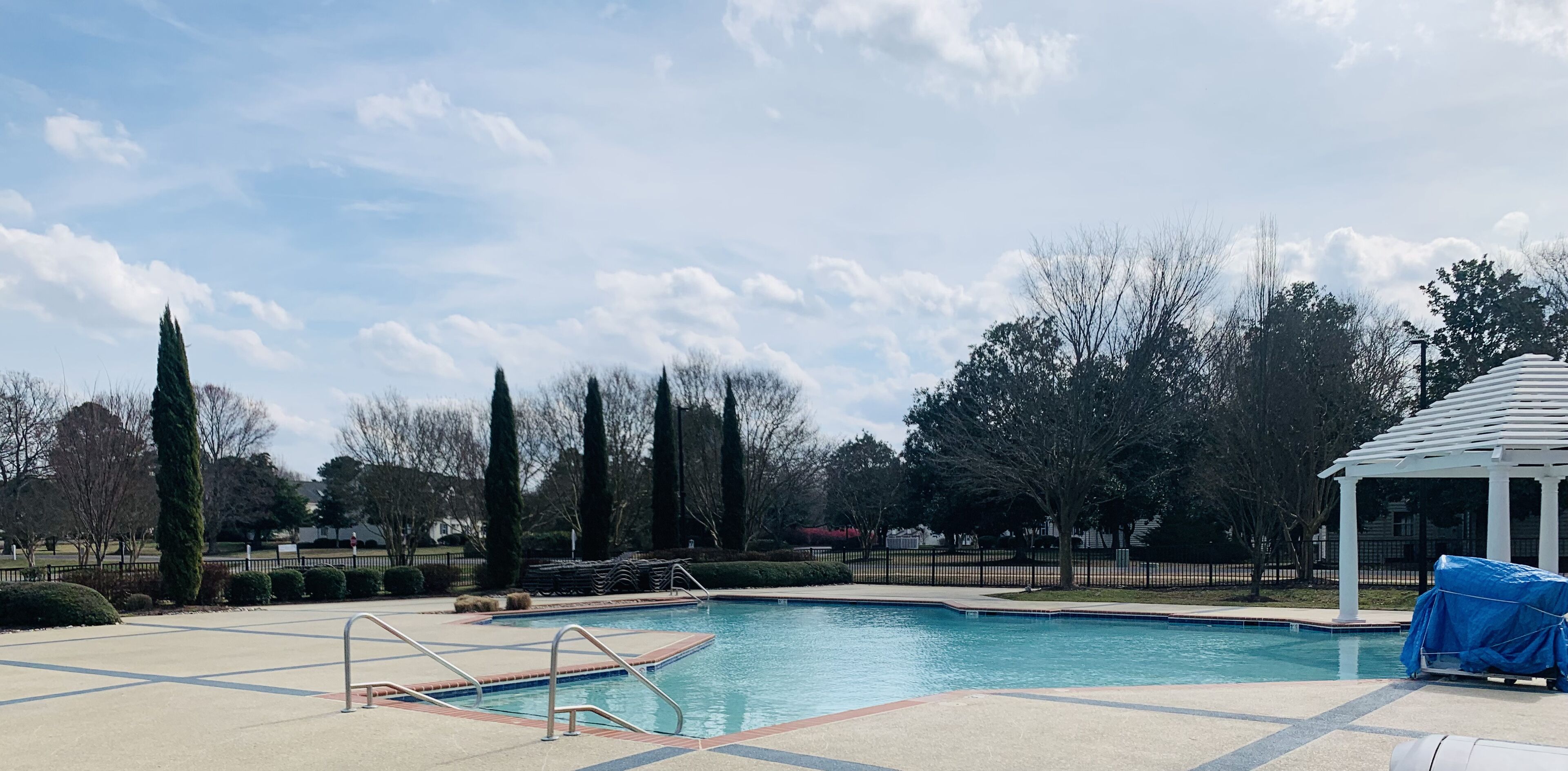 A swimming pool with a pergola and a gazebo in a landscaped area.