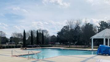A swimming pool with a pergola and a gazebo in a landscaped area.