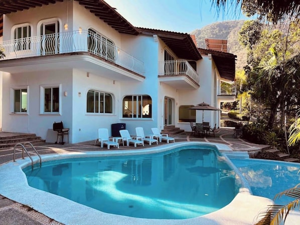 A two-story house with a swimming pool, outdoor seating, and a view of the surrounding landscape. - Villa Martha Garza Blanca with Chef & Full Staff (Puerto Vallarta)