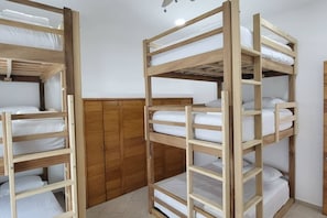 Quarto com duas beliches, guarda-roupa de madeira e chão em azulejo.