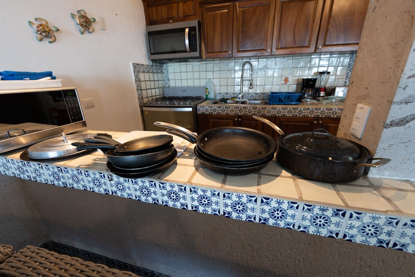 Une cuisine équipée d’un four à micro-ondes, d’une cuisinière et de divers ustensiles de cuisine posés sur le plan de travail.