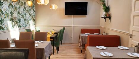 A restaurant with wooden floors, tables with white tablecloths, and chairs.