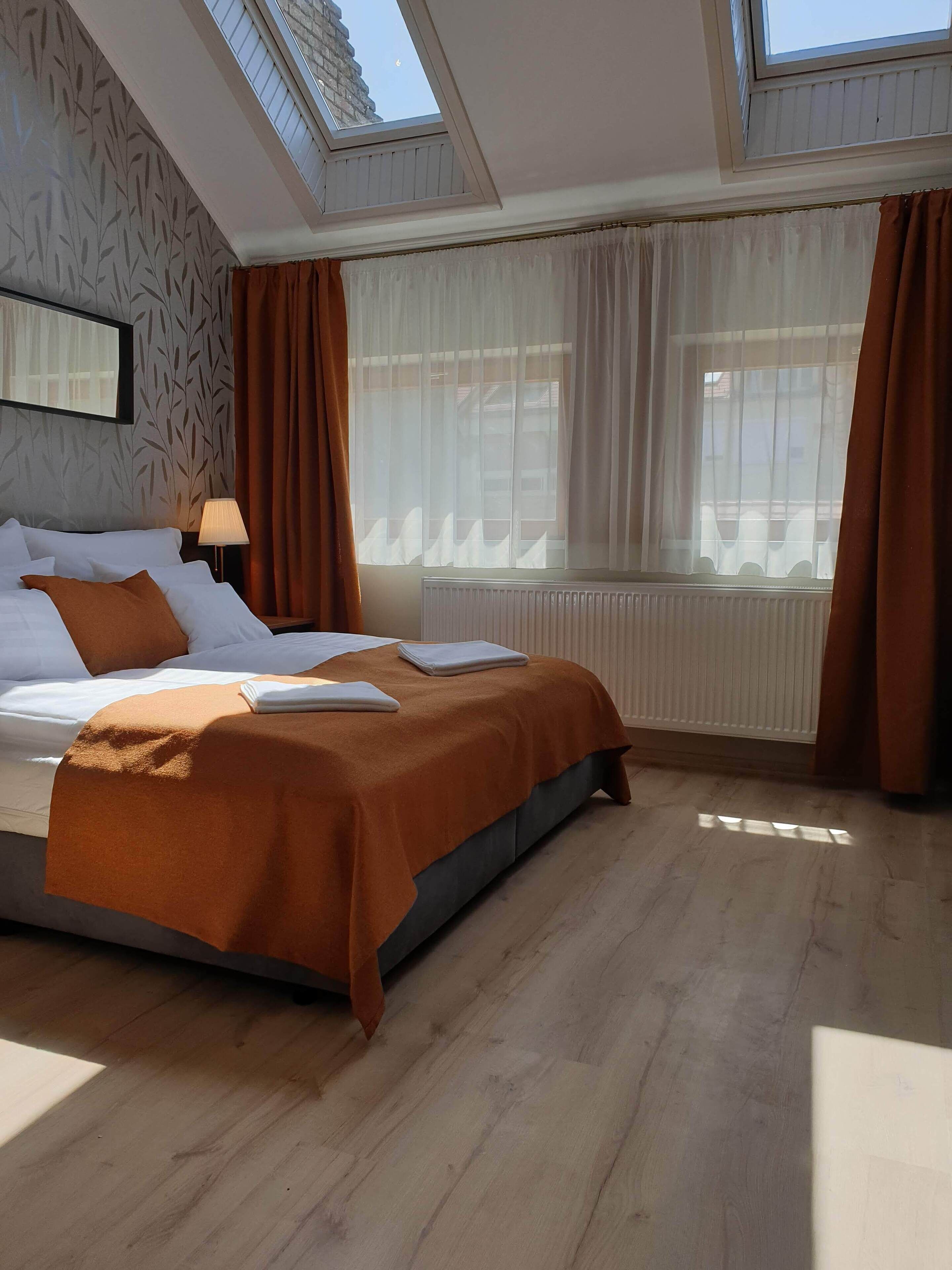 A bedroom with a bed, a radiator, and a window with curtains.