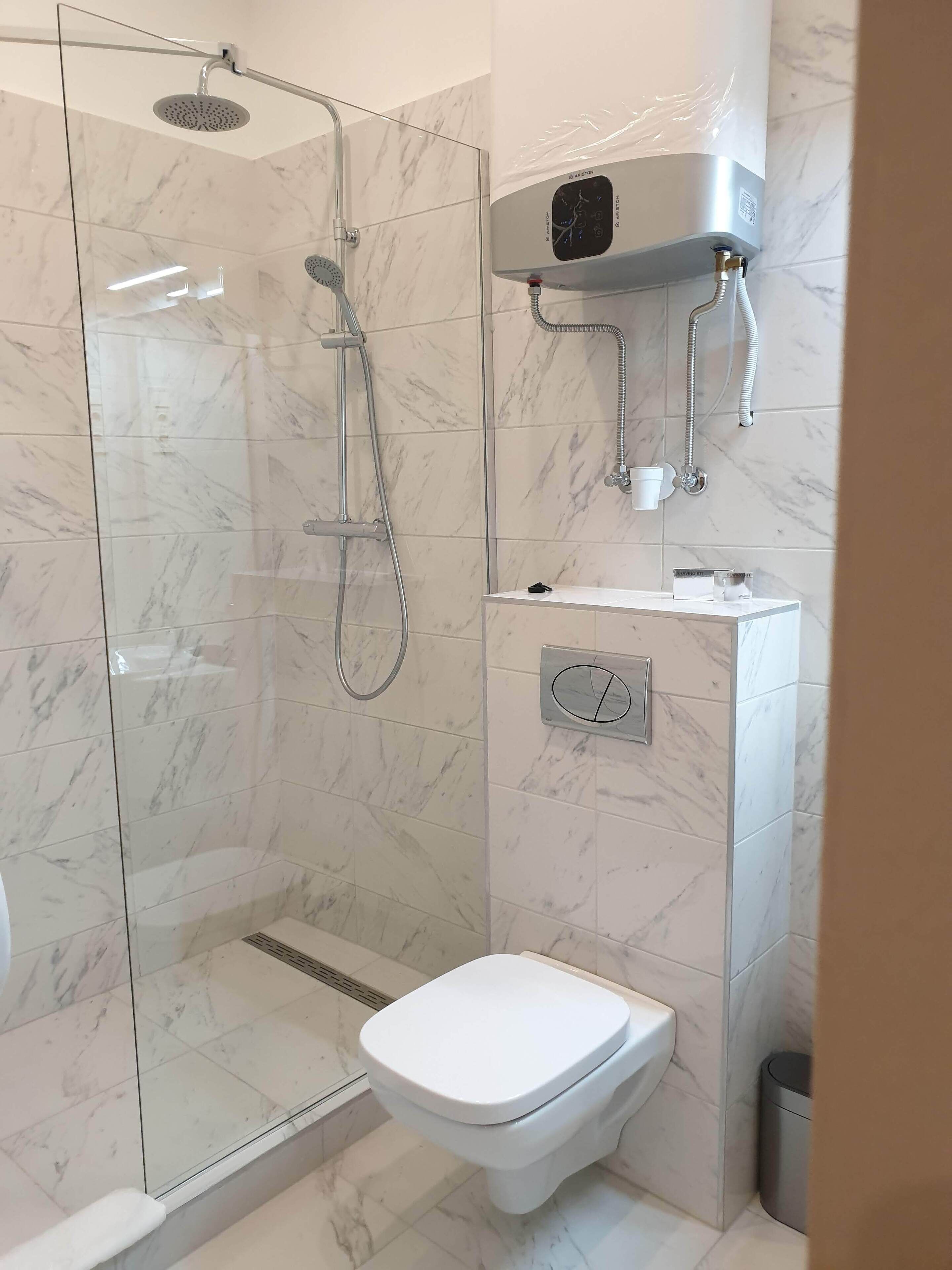 Casa de banho moderna com cabine de duche em vidro, sanita e lavatório com painel de controlo.
