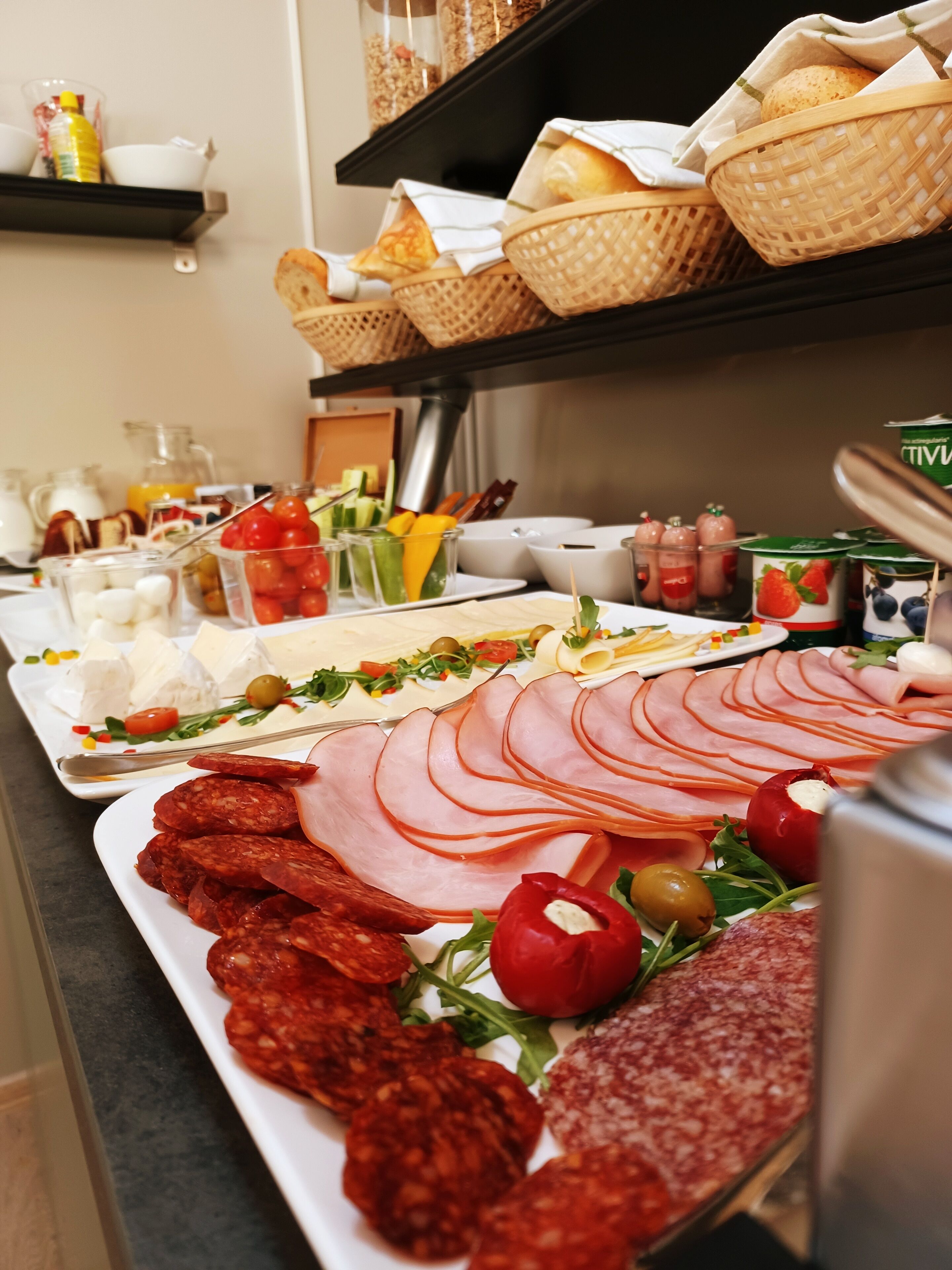 Un buffet proposant une variété de plats, notamment des viandes et des fromages en tranches, ainsi que des légumes.