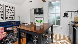 Una cocina moderna con una mesa de madera, un horno empotrado y un televisor sobre la encimera.