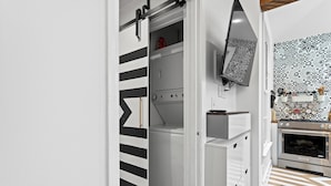 Una cocina compacta con horno integrado, microondas y una pequeña encimera.