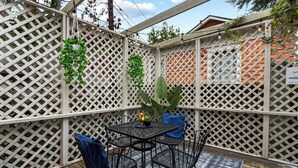 Un patio con una mesa y sillas, rodeado por un cerramiento de celosía.