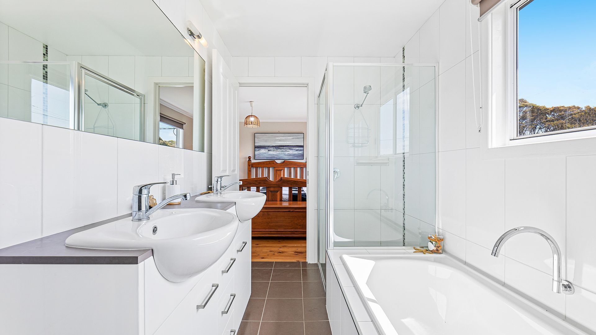 Une salle de bain moderne dotée d’une grande baignoire, de deux lavabos et d’une cabine de douche en verre.
