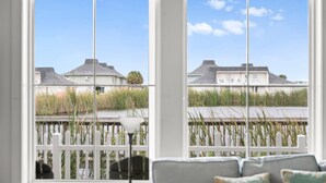 Una habitación con vista a una casa, una cerca blanca y una lámpara.