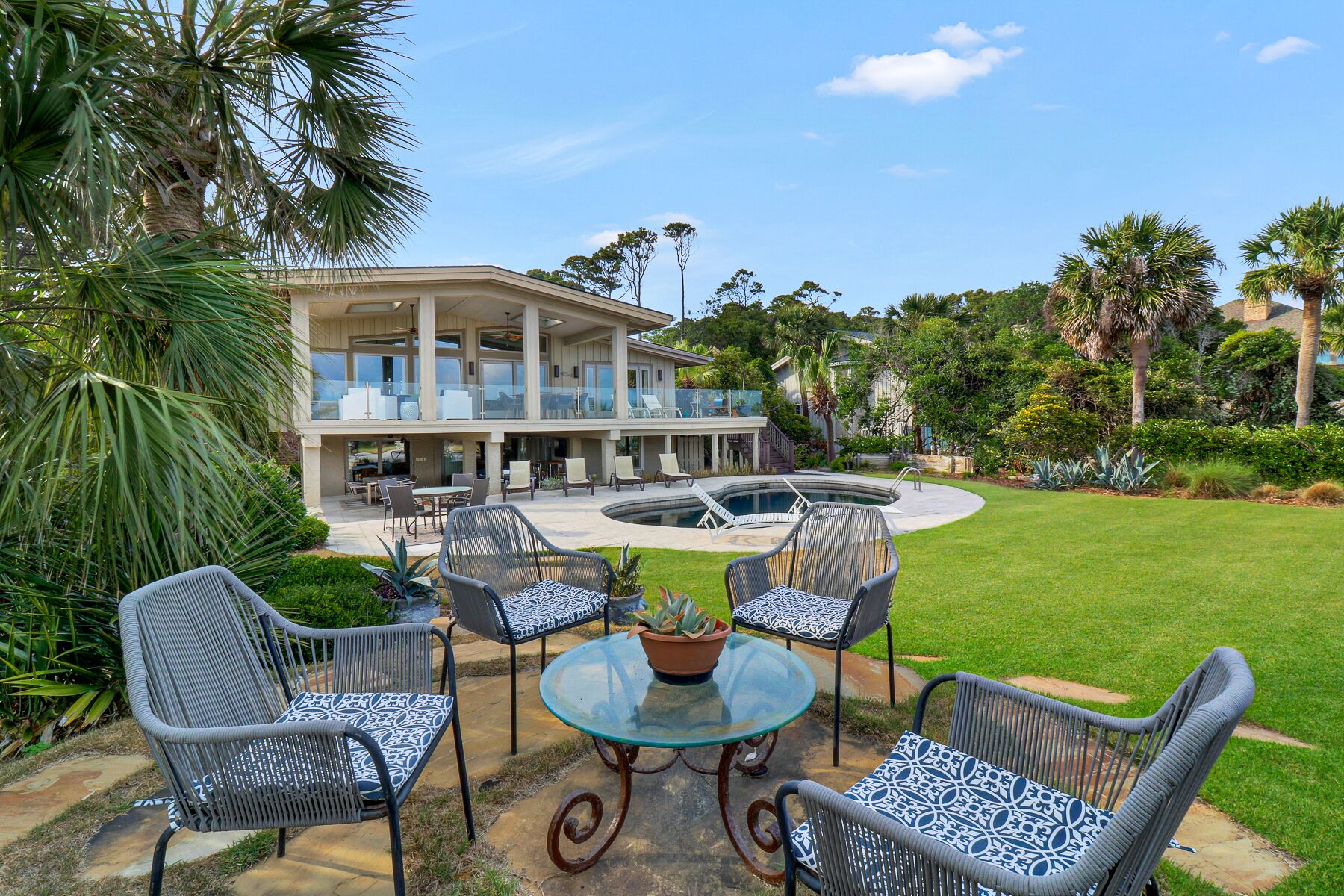 A two-story house with a balcony, a swimming pool, and outdoor furniture.