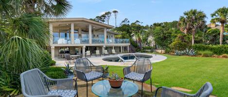 A two-story house with a balcony, a swimming pool, and outdoor furniture.
