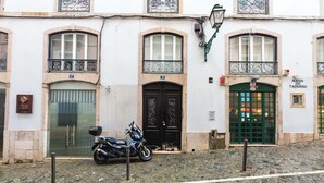 A building with two doors, a motorcycle parked in front, and a cobblestone street.