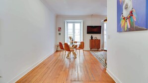 Un coin repas avec un plancher en bois, une table ronde entourée de quatre chaises et un téléviseur fixé au mur.