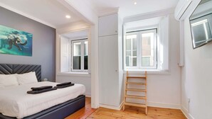 Une chambre à coucher avec un lit, une fenêtre, une échelle et un tableau accroché au mur.