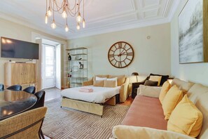 Una habitación de hotel moderna con cama, sofá, televisor y un reloj de pared grande.
