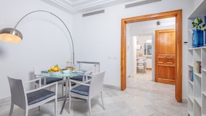 A dining area with a round table, chairs, and a fruit bowl. There is a wooden door leading to another room. - L'Oiseau Bleu Marsa Plage  (La Marsa)