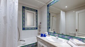 A bathroom with a bathtub, a sink, and a large mirror. - L'Oiseau Bleu Marsa Plage  (La Marsa)
