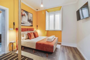 Ein Schlafzimmer mit einem Bett, einem Fenster, einem Gemälde und einem Fernseher an der Wand.