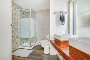A modern bathroom with a glass shower enclosure, a toilet, a sink with a wooden vanity, and a towel rack. - Bairro Alto | 4 Bedrooms + 4 Baths | Sleeps 8 (Lisboa)