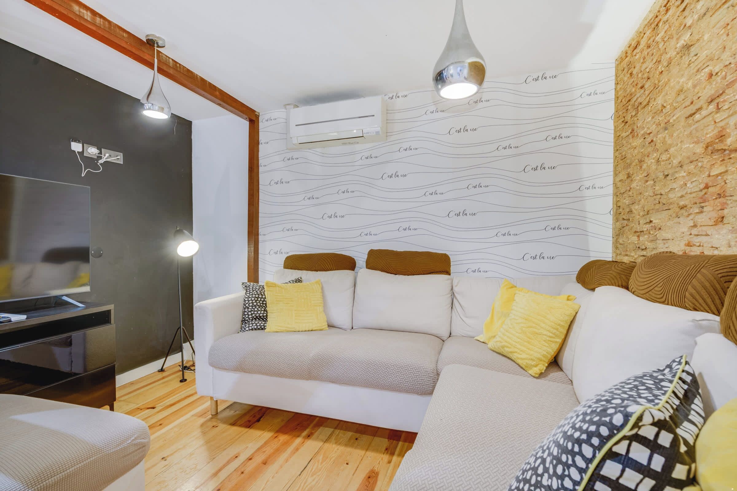 Una sala de estar con un sofá, un televisor y una pared con diseño.