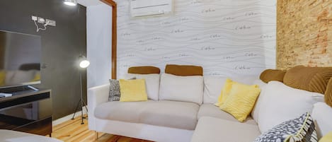 Ein Wohnzimmer mit einer Couch, einem Fernseher und einer Wand mit Muster.