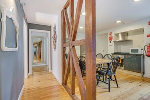 A modern kitchen with wooden flooring, a dining area with chairs, and a visible fire extinguisher. - Bairro Alto | 4 Bedrooms + 4 Baths | Sleeps 8 (Lisboa)