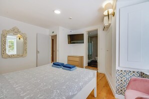 Ein Schlafzimmer mit einem Bett, einem an der Wand befestigten Fernseher und einer Tür zu einem Badezimmer.