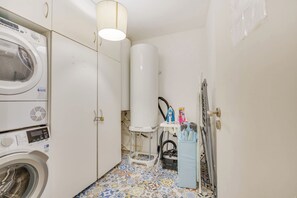 A laundry room with a washing machine, a dryer, a water heater, and an ironing station.