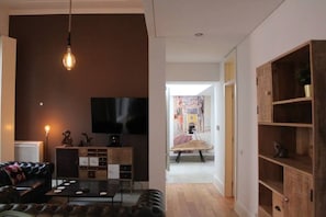 Una sala de estar moderna con un sofá de cuero, una mesa de centro, un televisor y un aparador de madera.