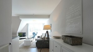 A modern living room with a television, a tripod, a lamp, and a wall-mounted sign. - Domizil Gartenstraße 4 Appartement 7 Treibgut (Timmendorfer Strand)